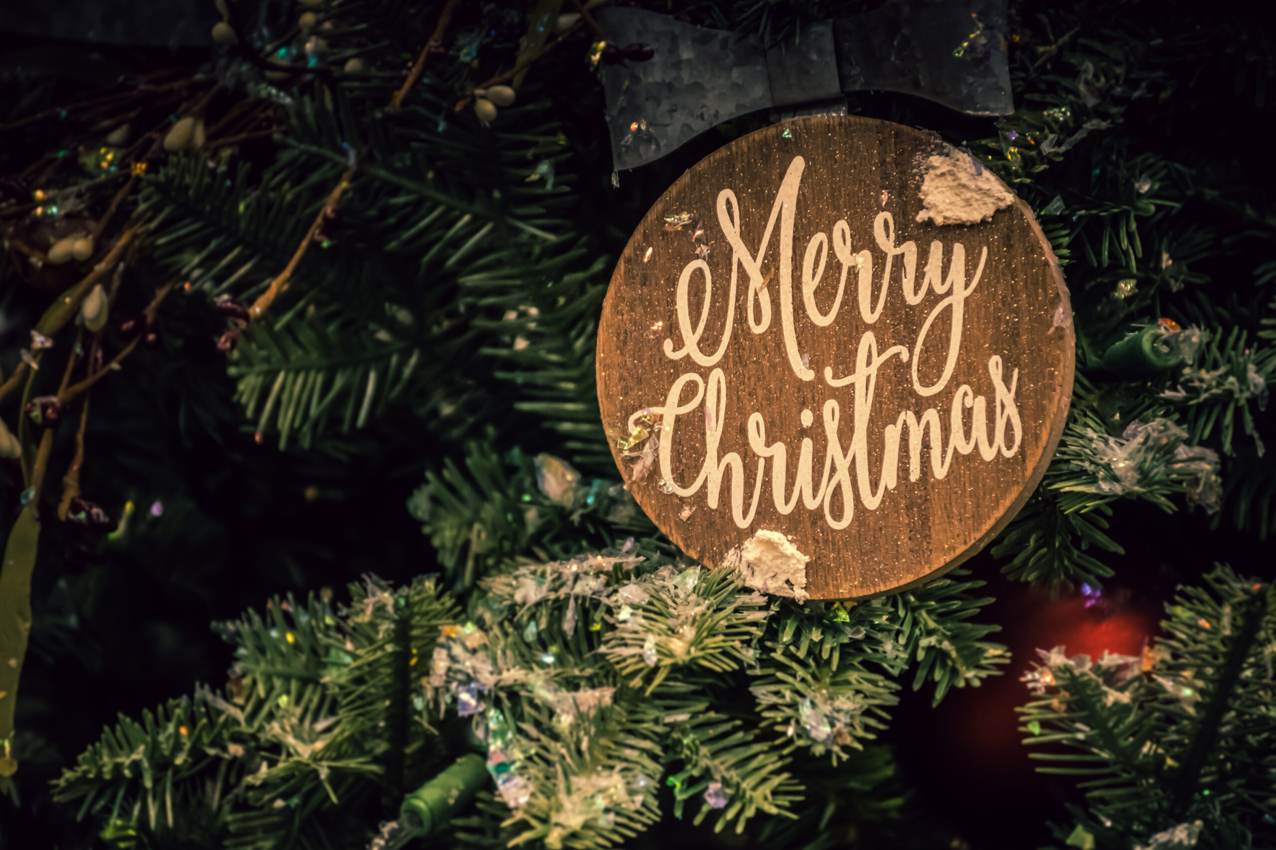 Wooden Merry Christmas sign on a green Christmas tree